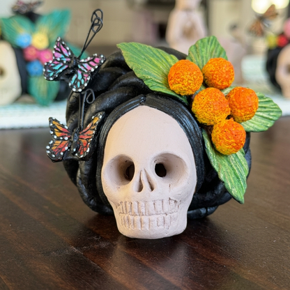 Handmade clay Catrina head from Mexico with colorful butterflies, green leaves, and orange flowers