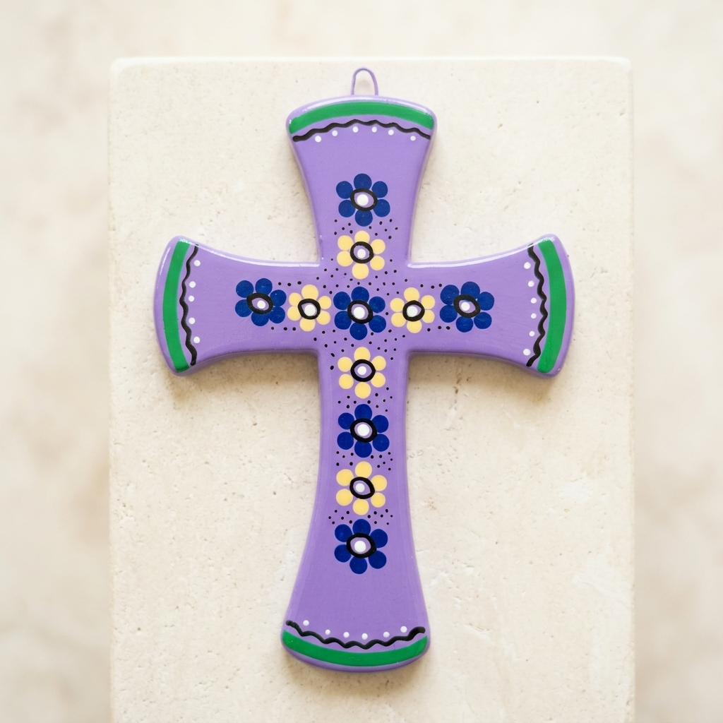 A hand-painted purple ceramic cross ornament with blue, yellow, and green floral patterns, displayed on a light beige stone block.